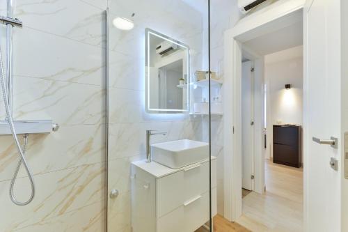 uma casa de banho branca com um lavatório e um chuveiro em Zara Lumina Apartment em Zadar