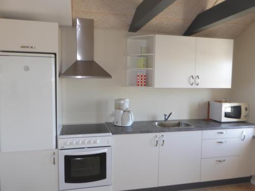 a kitchen with white cabinets and a sink at Harboøre Hotel in Harboør