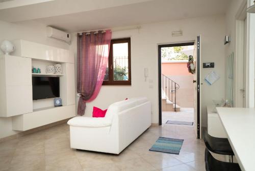 a living room with a white chair and a television at La Casetta di Chiara B&B in Polignano a Mare
