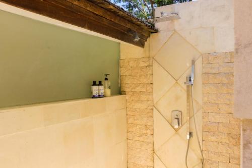 a bathroom with a shower in a stone wall at Chanteak Bali - Teak House 3 in Jimbaran