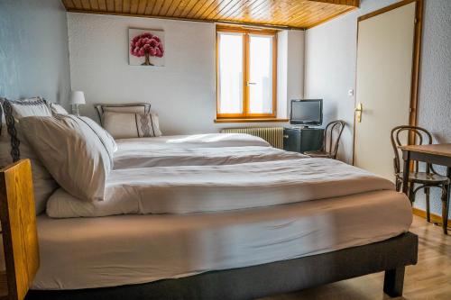 a large white bed in a bedroom with a window at Hôtel Au Vieux Moulin in Lapoutroie