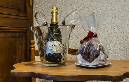 a glass vase with a bottle of wine on a table at Hôtel Au Vieux Moulin in Lapoutroie