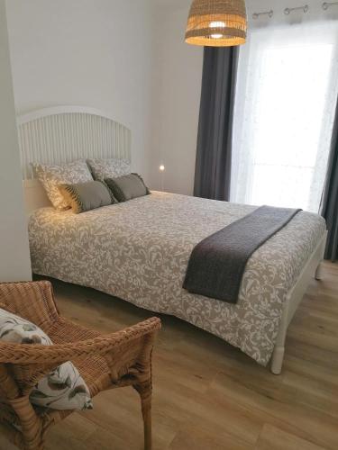 a bedroom with a bed and a chair in it at Apartamento Vilamar in Vila Nova de Milfontes