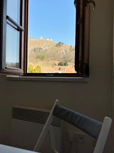 a room with a window and a chair looking at a mountain at Garni pension U svatého Urbana in Mikulov