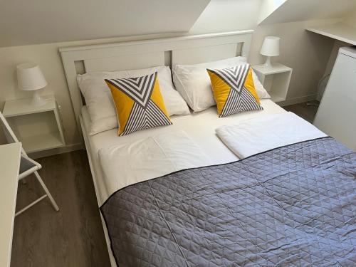 a bedroom with a bed with yellow and white pillows at Garni pension U svatého Urbana in Mikulov