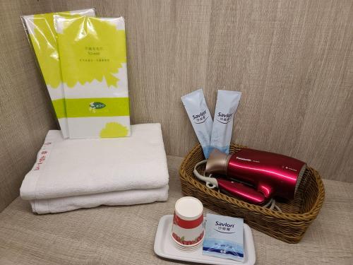a basket with towels and a bottle of lipstick and a cup at Love Happiness Inn in Suao