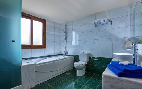 a bathroom with a tub and a toilet and a sink at Vasia Villas in Milatos