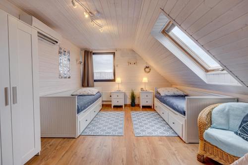 a attic bedroom with two beds and a window at Dom Wakacyjny Baltic Home & Dom Baltic Home Garden Inn in Zastań