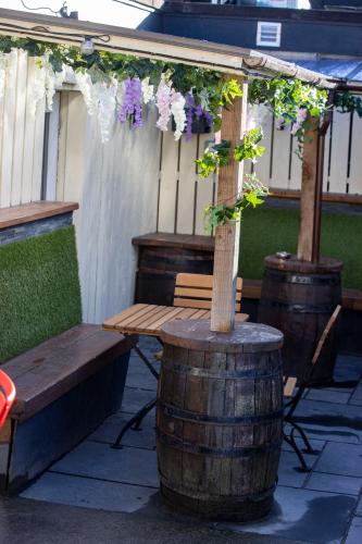 a wooden bench and a tree in a barrel with flowers at The Waverley Hotel in Callander