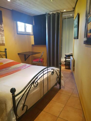 Un dormitorio con una cama y una mesa. en Chambre d'hôtes Le Cyprès Bleu, en Roussillon en Isère