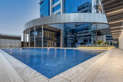 een groot gebouw met een zwembad ervoor bij Somerset Downtown Al Khobar in Al Khobar