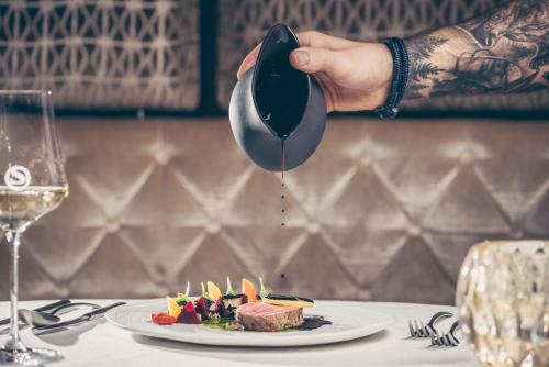 a person is pouring sauce into a plate of food at Stock Resort in Finkenberg