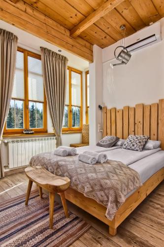 a bedroom with a large bed and a wooden ceiling at Niedźwiedzia Residence Garden Sauna in Poronin