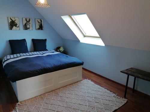 Un dormitorio con una cama con paredes azules y una ventana en Maison confortable séjour spacieux, belle terrasse avec grand jardin avec jeux extérieurs près Bayeux et Omaha Beach en Saonnet