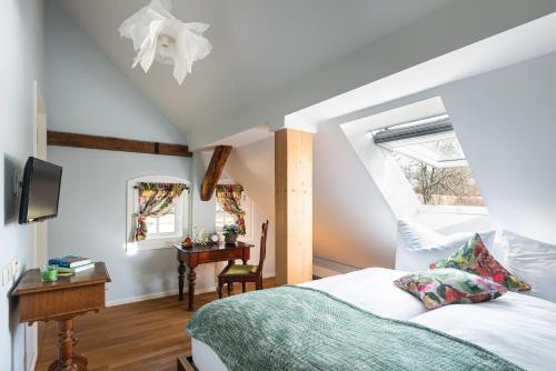um quarto com uma cama, uma mesa e uma janela em Klostergartenhotel Marienfließ em Stepenitz