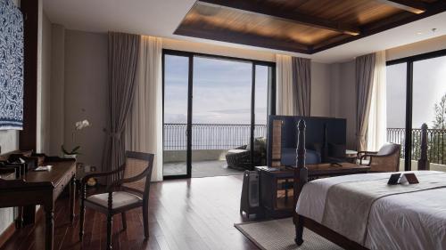 a hotel room with a bed and a desk and a balcony at Plataran Bromo in Bromo