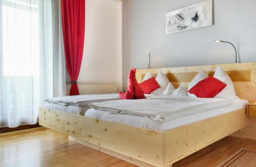 1 dormitorio con cama de madera y almohadas rojas en Gästehaus Bischof, en Schöder