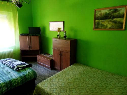a bedroom with green walls and a bed and a dresser at Szakál Vendégház in Aggtelek
