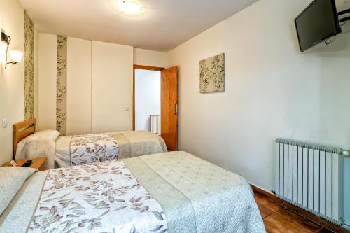 a room with two beds and a flat screen tv at Pension La Playa in Talavera de la Reina
