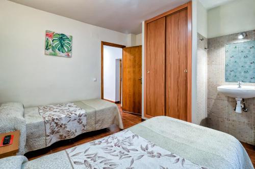 a hotel room with two beds and a sink at Pension La Playa in Talavera de la Reina