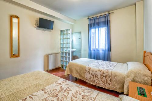 a hotel room with two beds and a television at Pension La Playa in Talavera de la Reina