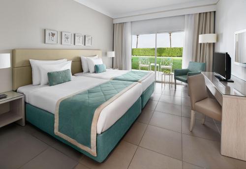 a hotel room with a large bed and a desk at JAZ Aquaviva in Hurghada