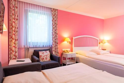 a hotel room with two beds and a chair at Hotel Heldt in Bremen