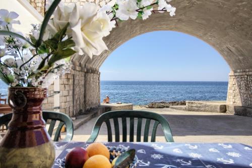 a table with a vase of flowers and fruit on it at La casa in riva al mare by LoveSud in Leuca