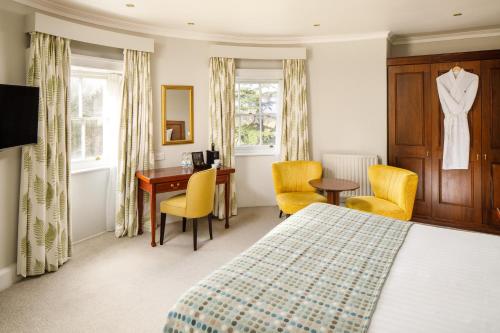 a hotel room with a bed and a desk and chairs at Mercure Gloucester Bowden Hall Hotel in Gloucester