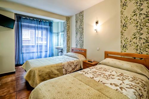 a hotel room with two beds and a window at Pension La Playa in Talavera de la Reina