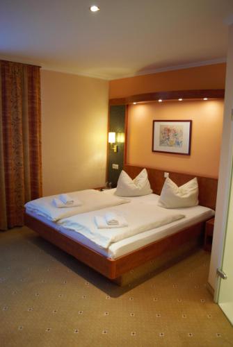 a bedroom with a large bed with white sheets at Hotel am Bahnhof in Weilburg