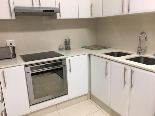 a kitchen with white cabinets and a sink at Ballito Sands in Ballito