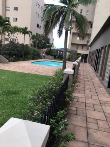 a sidewalk with a palm tree next to a building at Ballito Sands in Ballito