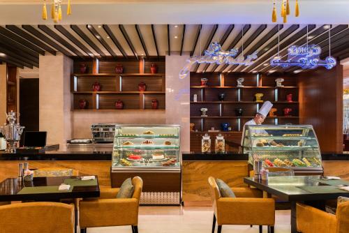 a restaurant with two tables and a counter with food at Dusit Thani Abu Dhabi in Abu Dhabi