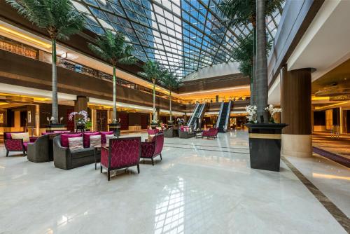 a lobby with tables and chairs and a glass ceiling at Dusit Thani Abu Dhabi in Abu Dhabi