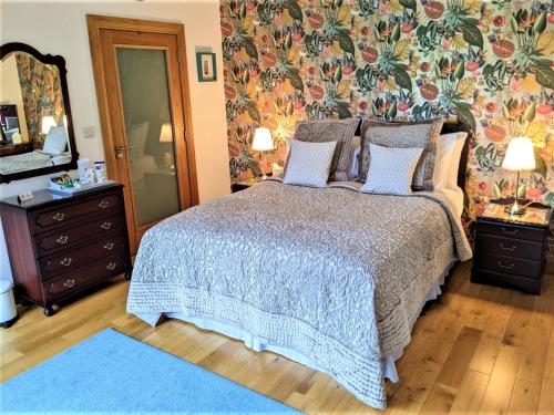 een slaapkamer met een bed en een spiegel en een blauw tapijt bij BallyCairn House in Larne