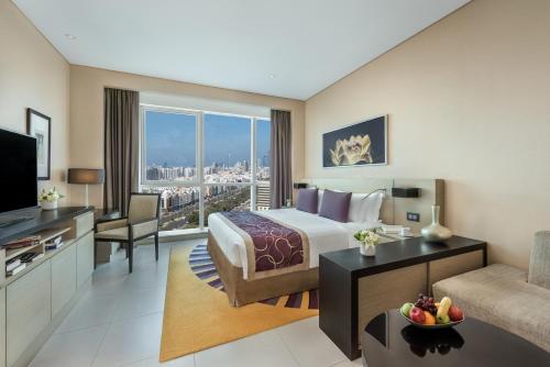 a hotel room with a king sized bed and a television at Dusit Thani Abu Dhabi in Abu Dhabi