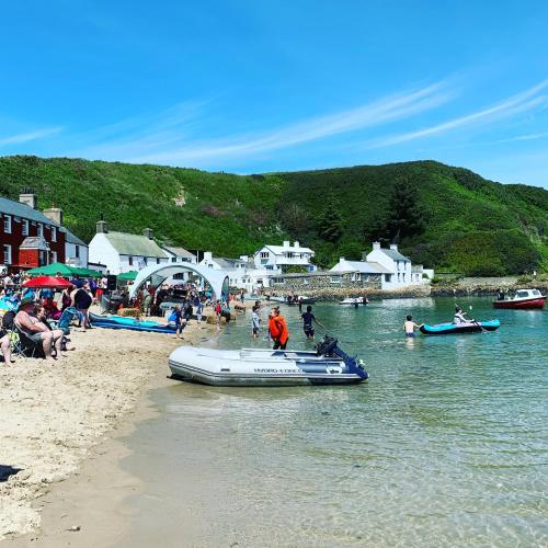 people on a beach with a boat in the water at Swyn-Y-Mor in Morfa Nefyn