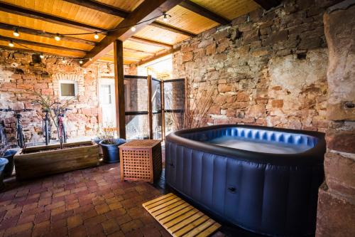 Una gran bañera azul en una habitación con una pared de piedra. en Appartements et Séminaires Griotte et Cannelle, en Bergbieten