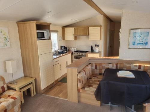 a small kitchen with a table in a room at S460 8 BERTH CARAVAN ON THE GOLDEN PALM CHAPEL ST LEONARDS in Chapel Saint Leonards