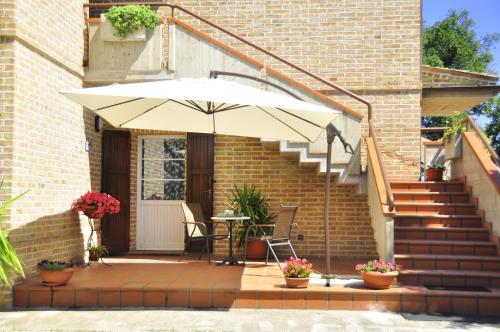 un patio con sombrilla, mesa y escaleras en SCHITO 114 Apartments, en Treia