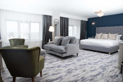 Erris Coast Hotel في Geesala: غرفة نوم بسرير واريكة وكرسي