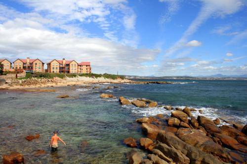 a man standing in the water on a rocky beach at 2 Geckos in Mossel Bay