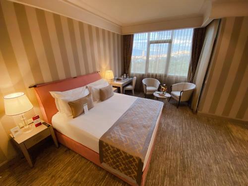 a hotel room with a bed and a table and chairs at Kaya Izmir Thermal & Convention in Izmir