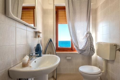 bagno con lavandino, servizi igienici e finestra di SARDINIA RE - Casa Anglona a Castelsardo