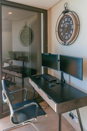 an office with two desks and a clock on the wall at Luxury Ocean View 1203 with Workspace, AC & Beachfront Location in Cape Town