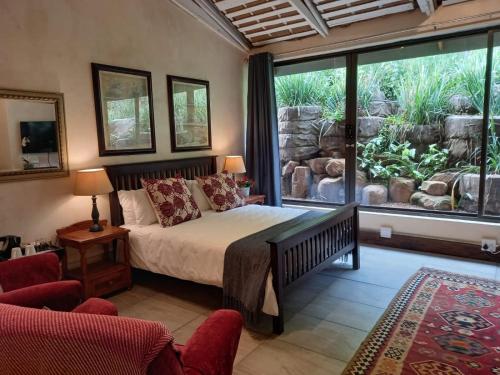 a bedroom with a bed and a large window at Ascot Bush Lodge & Spa in Pietermaritzburg