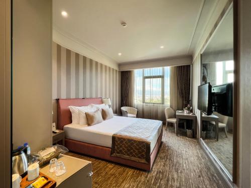 a hotel room with a bed and a flat screen tv at Kaya Izmir Thermal & Convention in Izmir
