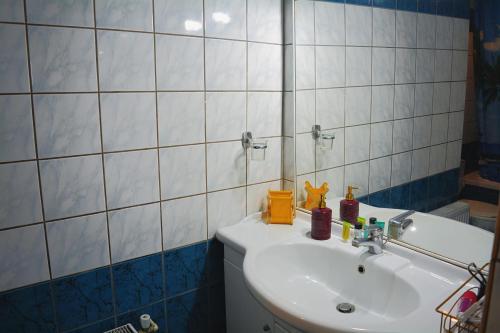 un bagno con lavandino bianco e parete piastrellata bianca di Moumouri's House a Gastouri