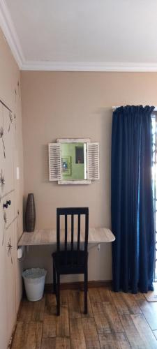 een stoel in een kamer met een tafel en een blauw gordijn bij Archer's Nest in Empangeni